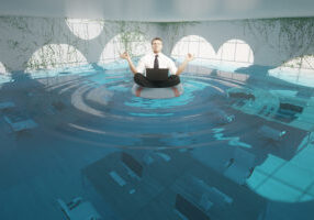 Businessman with laptop meditating on lifebuoy in abstract flooded office interior. 3D Rendering