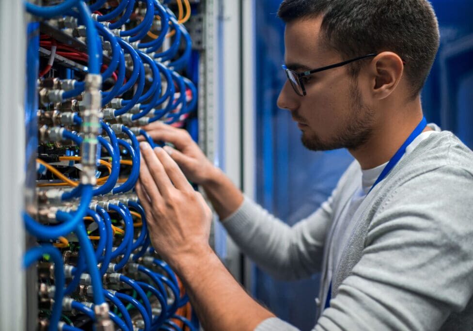 Side,View,Portrait,Of,Young,Man,Connecting,Wires,In,Server